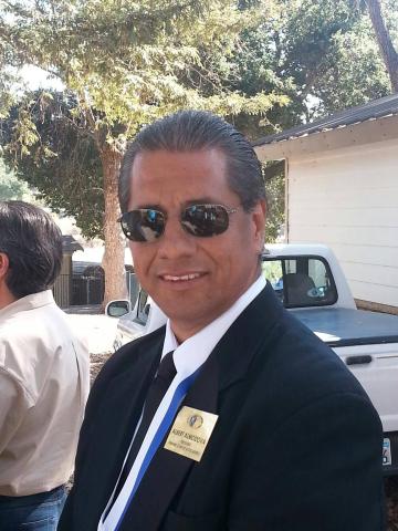 Atascadero Kiwanis member and 2025 Champion of the Community, Albert Almodova, wearing a suit, tie, name badge and sunglasses.
