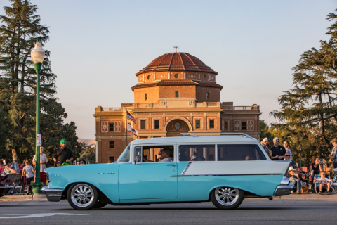 Classic car cruising on El Camino Real in front of the Sunken Gardens and Historic Atascadero City Hall Building.